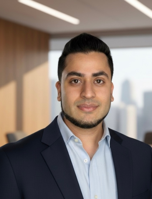 Male team member headshot Male team member with dark hair and neatly trimmed beard wearing a navy blazer and light blue shirt headshot
