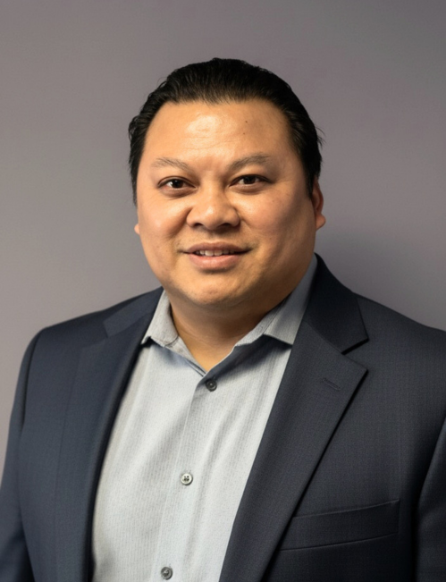 Male team member headshot Male team member with dark hair wearing a navy blazer and light blue shirt headshot