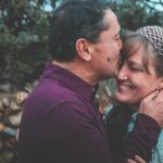 A loving couple shares a tender moment outdoors in a garden setting, expressing happiness and affection.